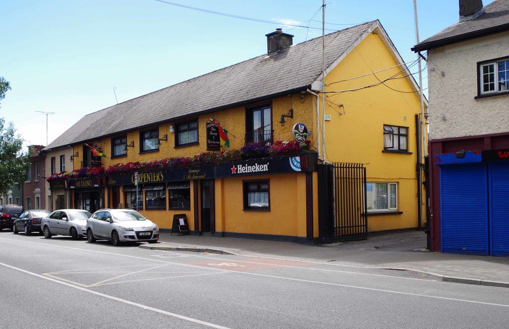 Carpenter's on Barrack Street: a long yellow building with hanging baskets over a red shopfront